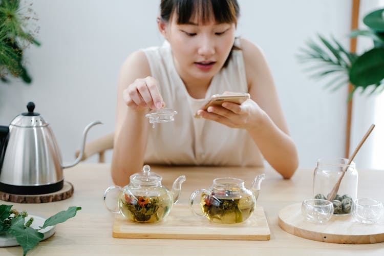 Woman Taking Photo On Mobile Of Tea In Teapot