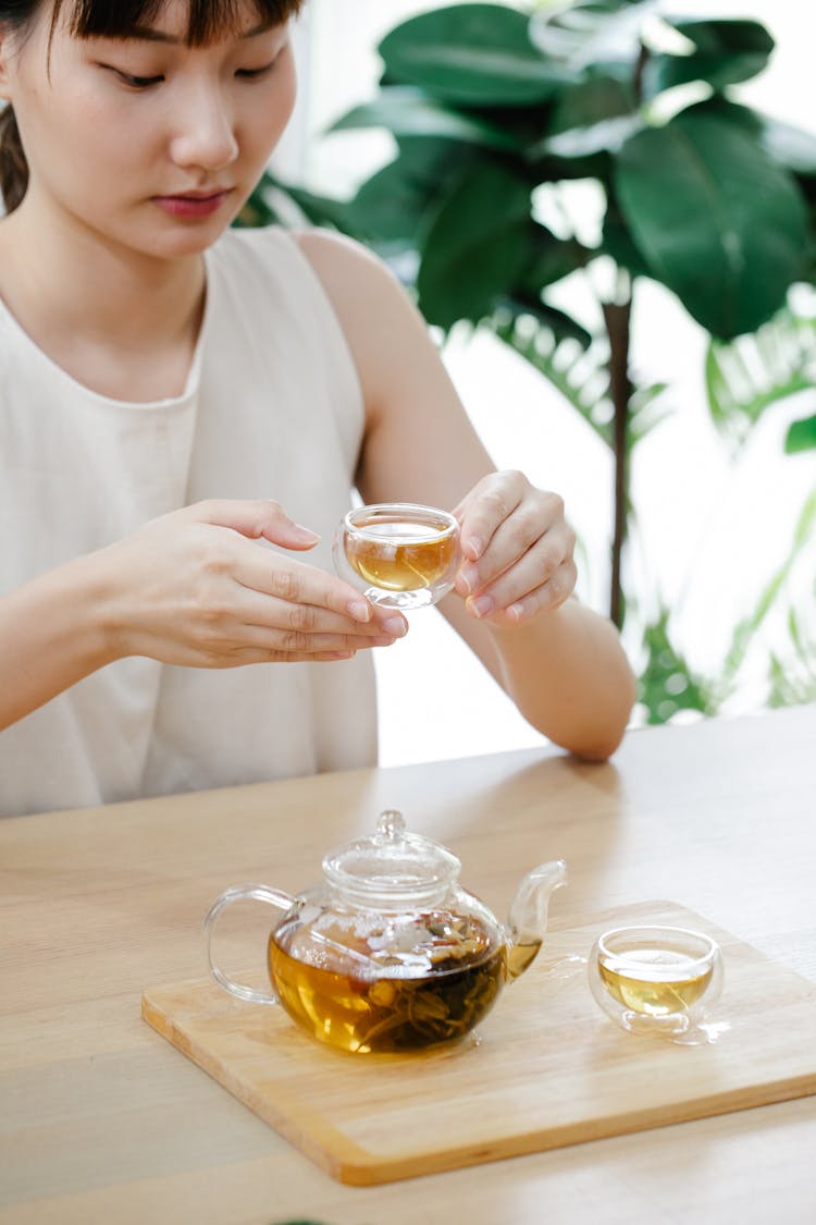 Woman Sitting At Table Drinking Tea