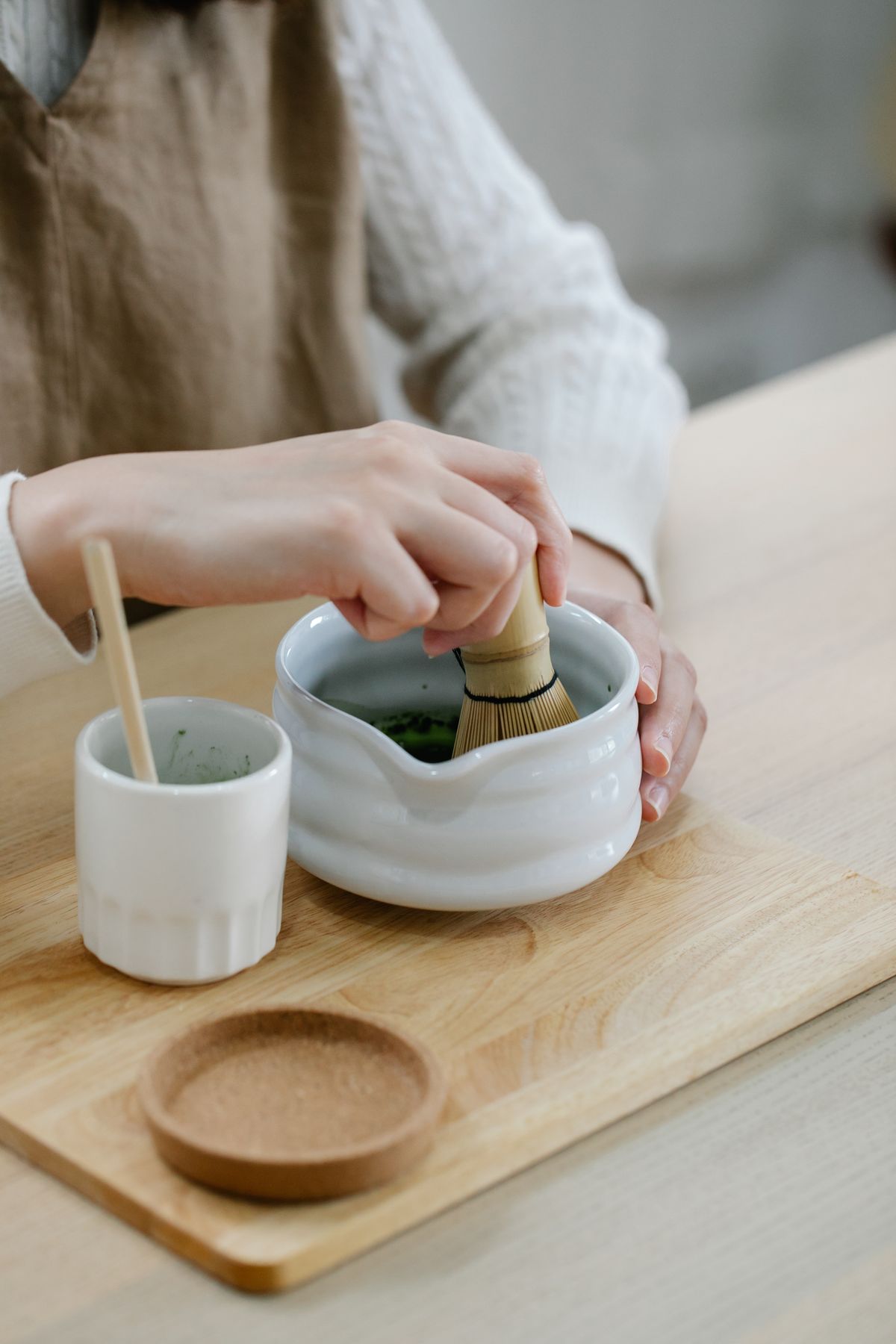 Hände bereiten Matcha in einem weißen Chawan zu – klassische Usucha-Zubereitung mit Chasen