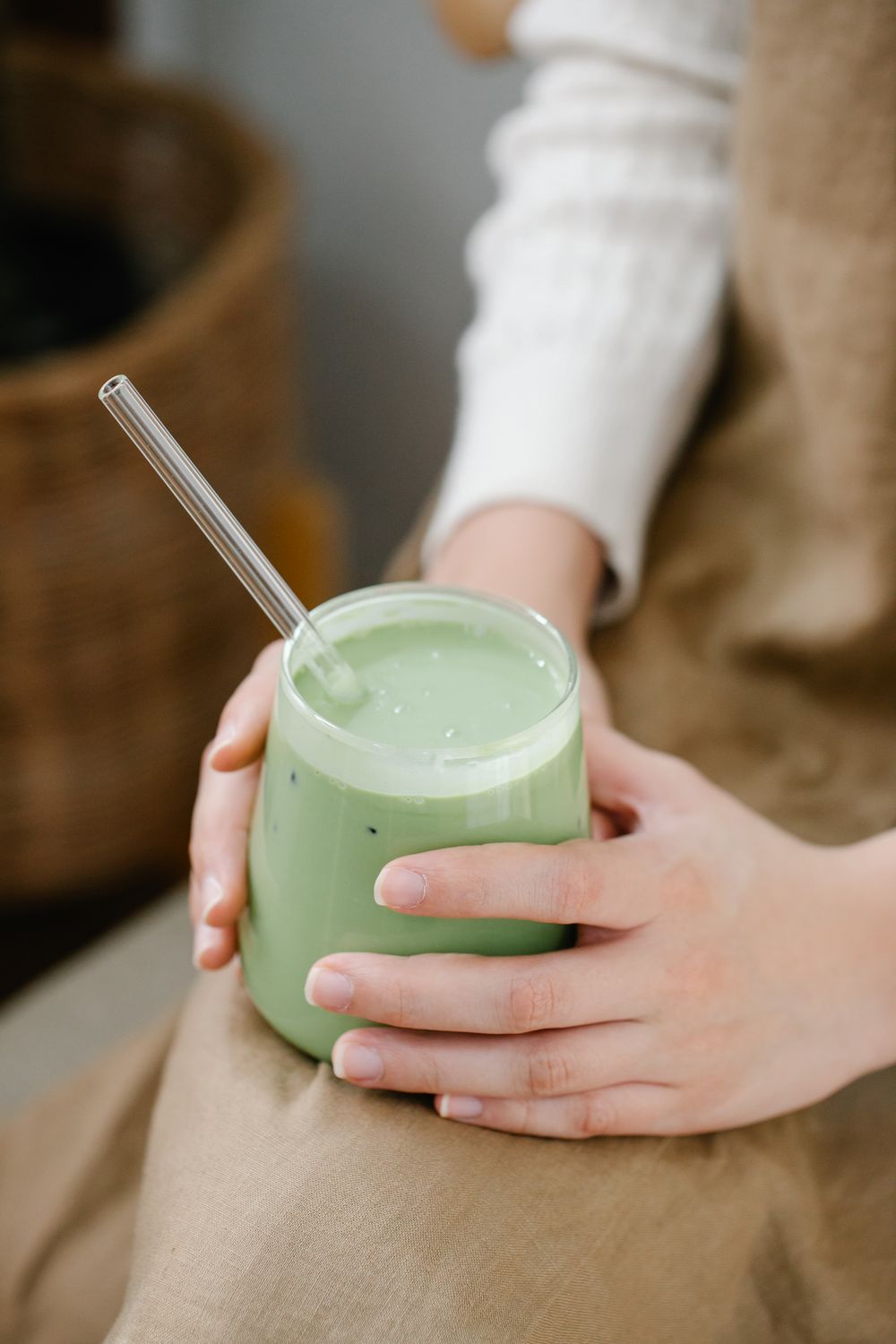 Hands holding a glass of green vegetable smoothie