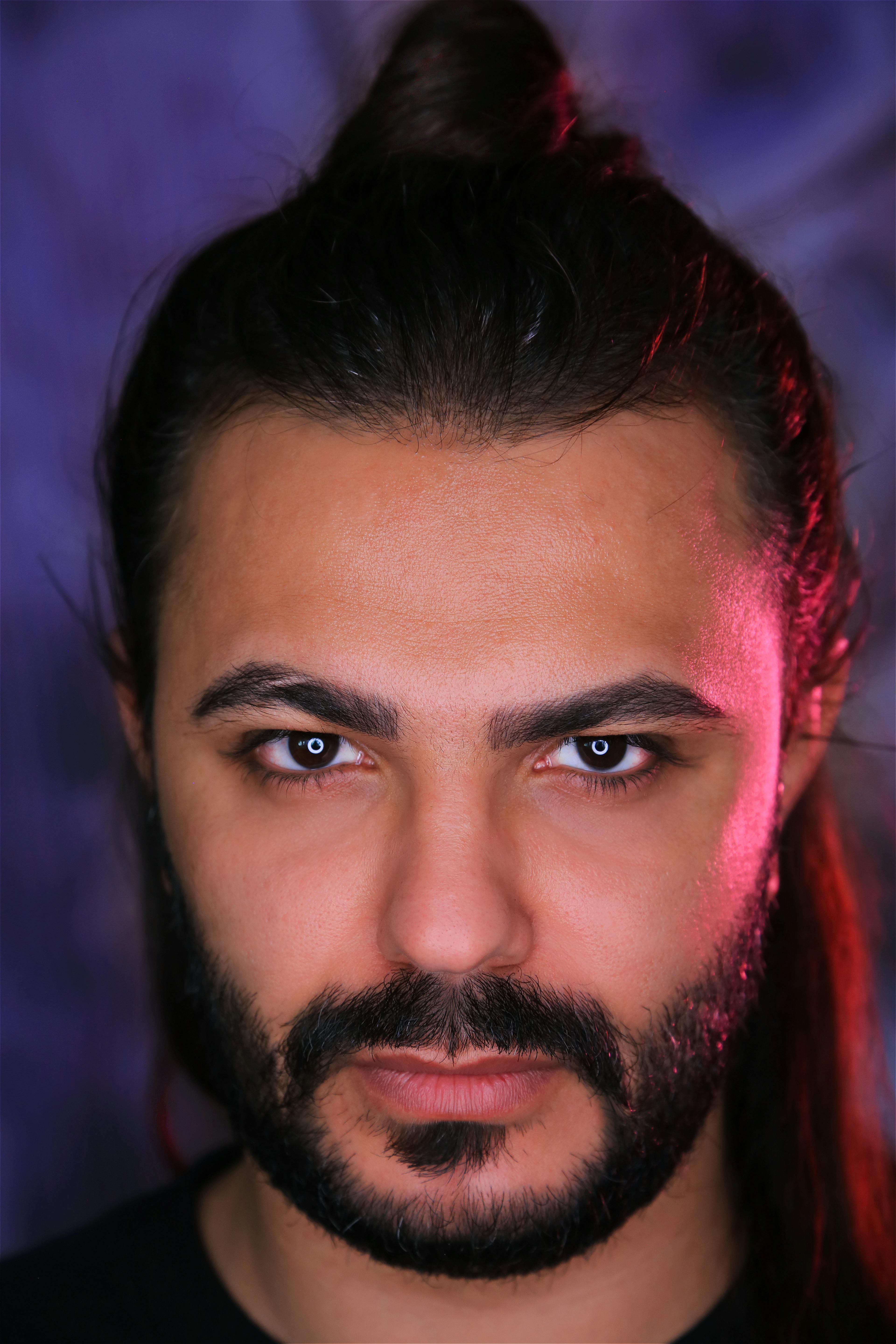 Close-up portrait of a handsome man with facial hair, intense eyes, and a focused expression.