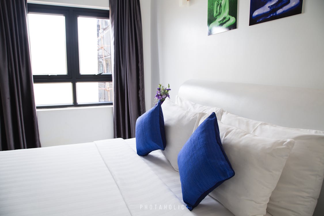 Pillows and cushions on a mattress in a room with windows