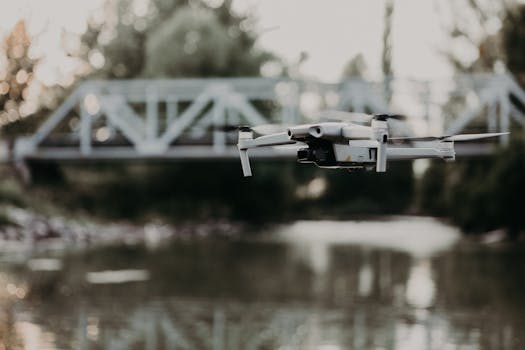 A modern drone captures stunning aerial views over a tranquil river and steel bridge.