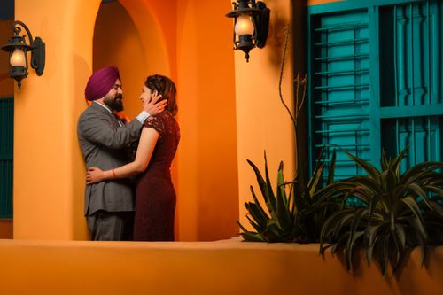 Free A loving Indian couple embracing outdoors against a vibrant orange and teal backdrop. Stock Photo