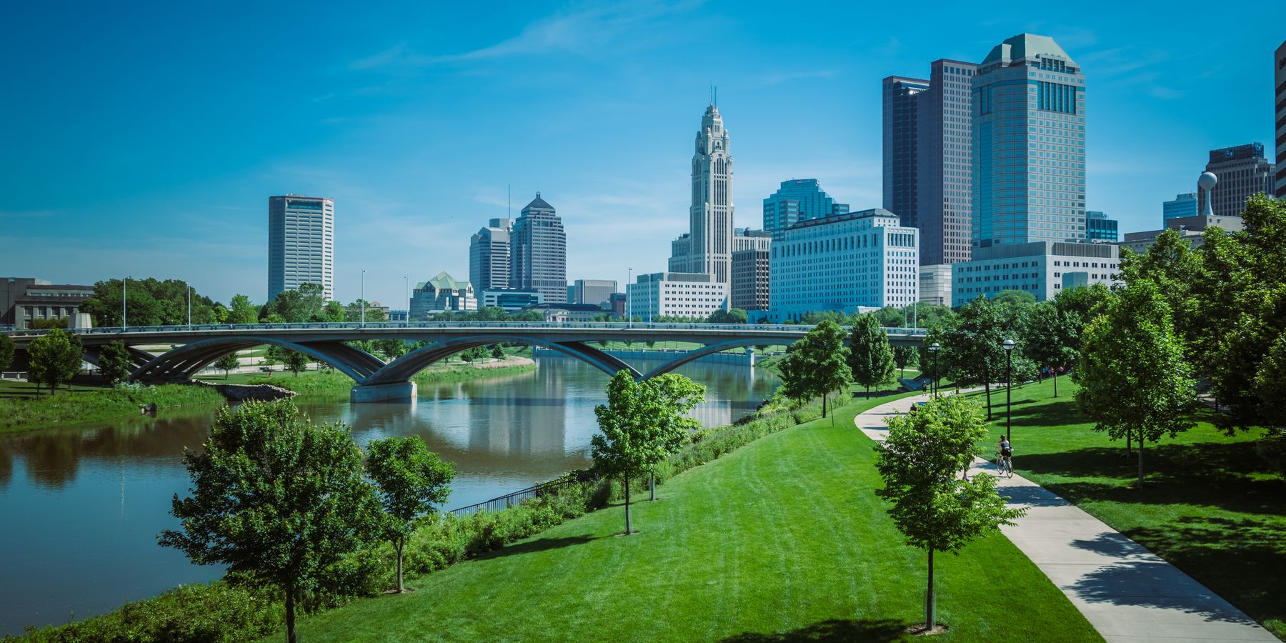 View of Columbus skyline with modern skyscrapers and green park along the river.