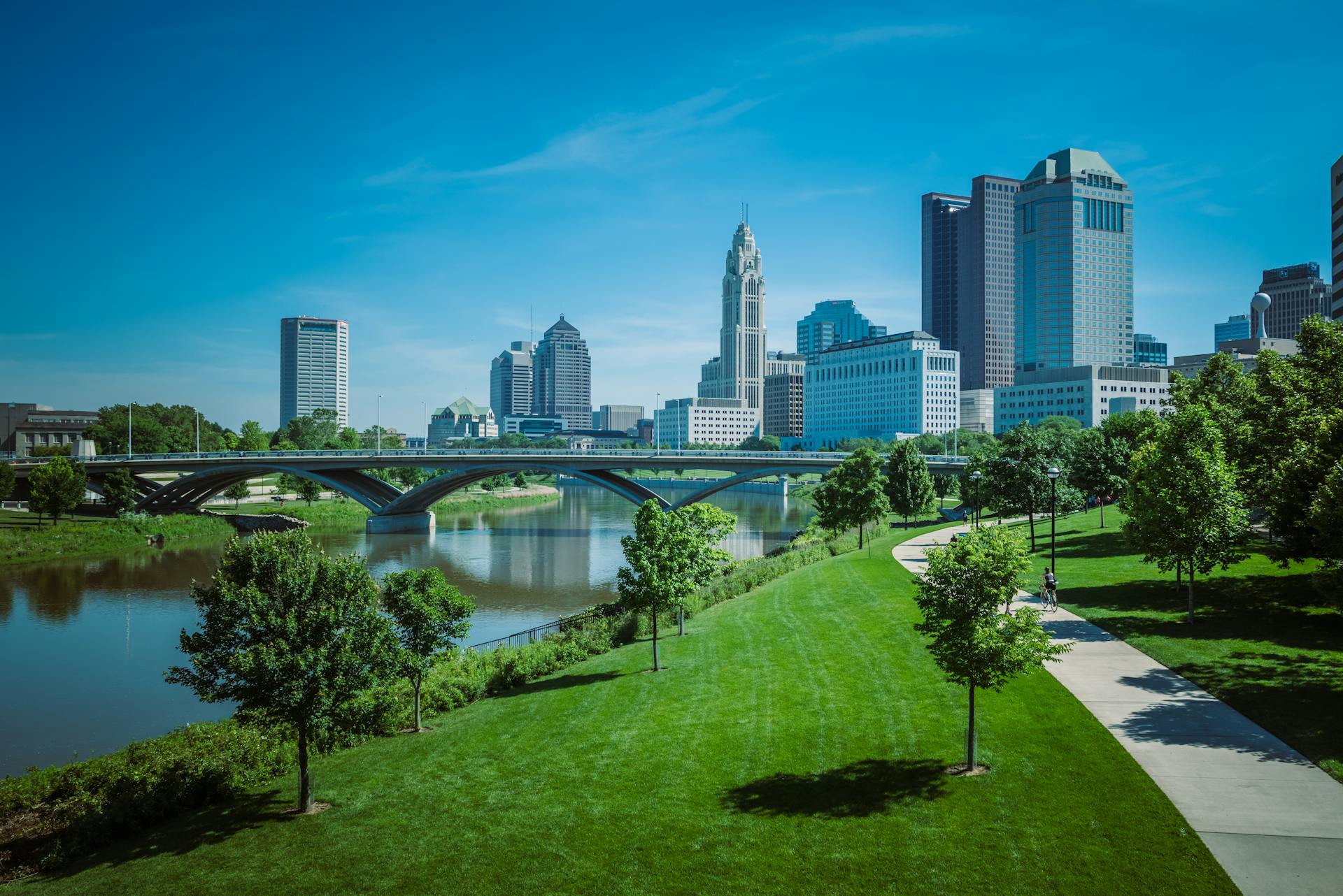 View of Columbus skyline with modern skyscrapers and green park along the river.