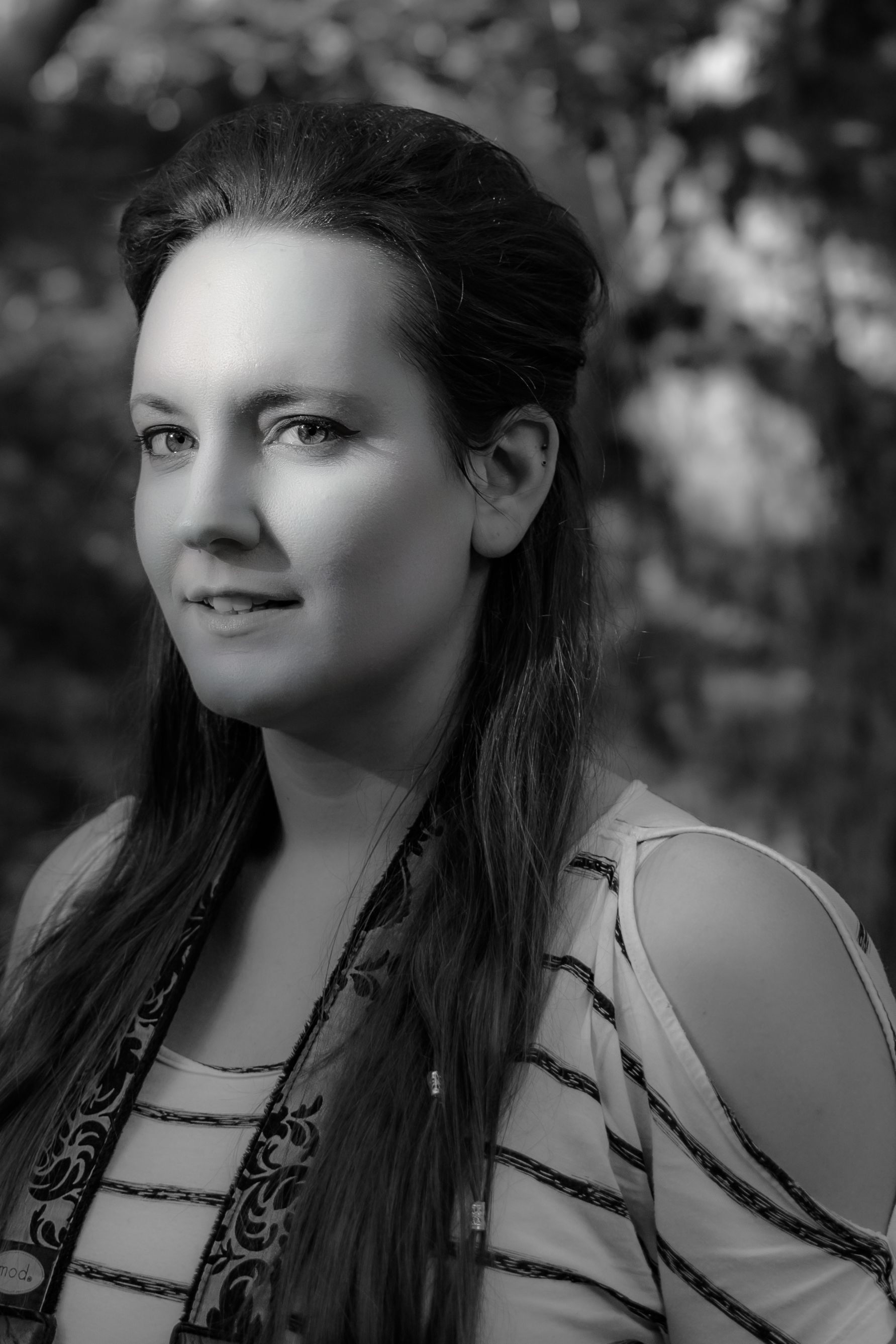 Monochrome portrait of a woman with long hair outdoors, featuring natural lighting and a calm expression.