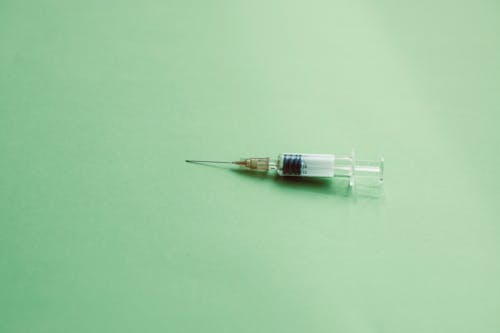 Close Up Photo of Syringe on Green Surface