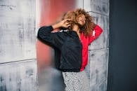 一位时尚女性在纹理丰富的城市墙壁前摆弄着卷发