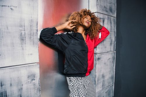 Free Fashionable woman posing with curly hair against a textured urban wall. Stock Photo