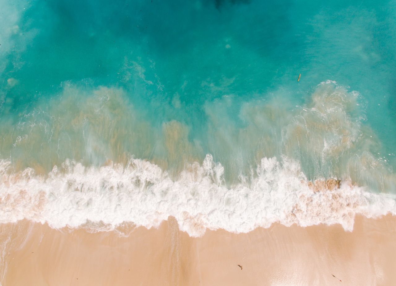 a stunning aerial view of turquoise waves crashing onto a sandy beach