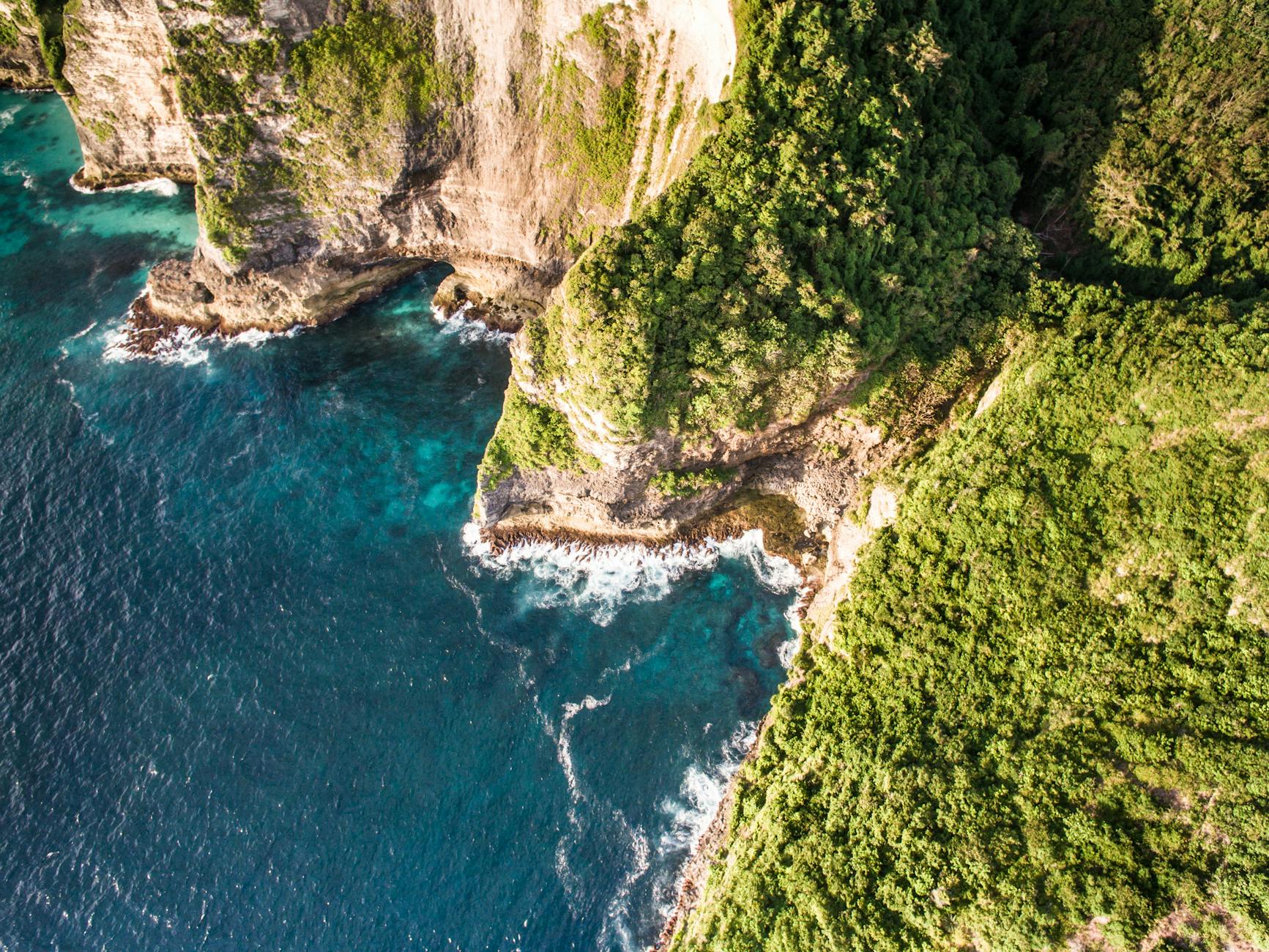 Dramatic aerial capture of rocky cliffs meeting the ocean, highlighting nature's rugged beauty.