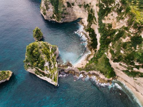 Free A stunning aerial photo capturing the rocky shoreline and pristine blue waters. Stock Photo