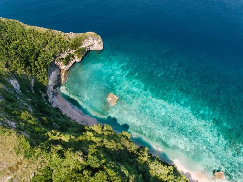 Free Breathtaking aerial view of a lush coastal cliff with turquoise ocean waters, perfect for nature lovers. Stock Photo