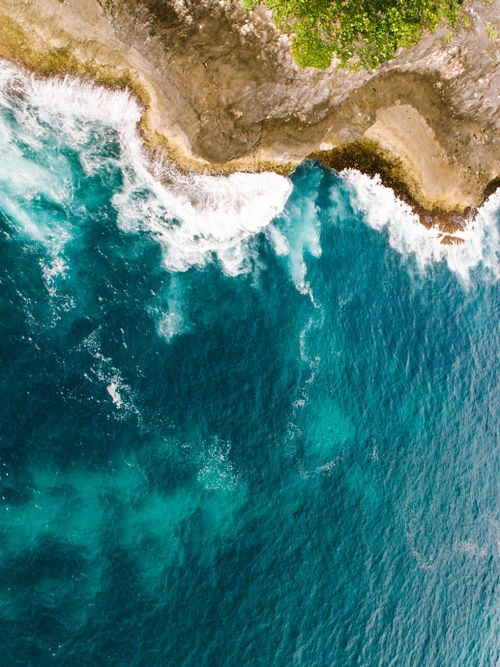 Free Explore the natural beauty with a stunning aerial view of turquoise sea waves crashing against the rugged coast. Stock Photo