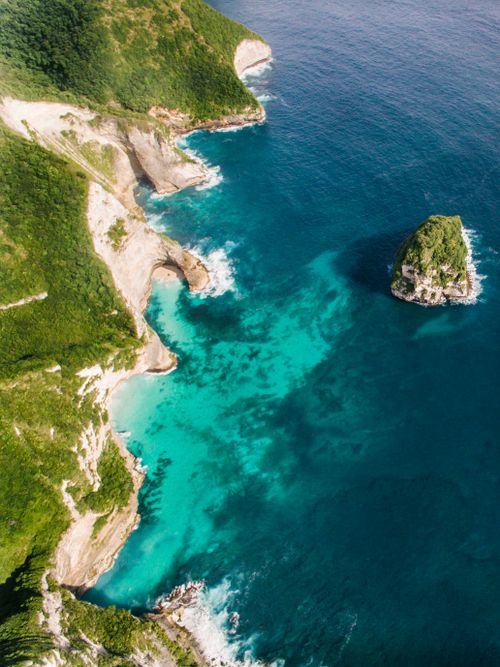 Free A breathtaking aerial shot of a coastline with vibrant turquoise waters and lush cliffs. Stock Photo