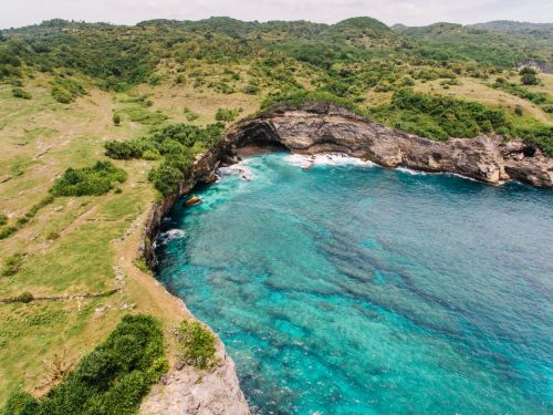Free A breathtaking aerial view of a tranquil turquoise lagoon surrounded by lush greenery and rocky formations. Stock Photo