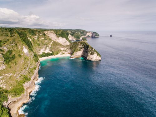 Free Breathtaking aerial shot of rugged coastal cliffs and clear blue ocean waters. Stock Photo