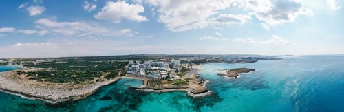 Free Scenic aerial view of a coastal city with clear turquoise waters under a bright sky. Stock Photo