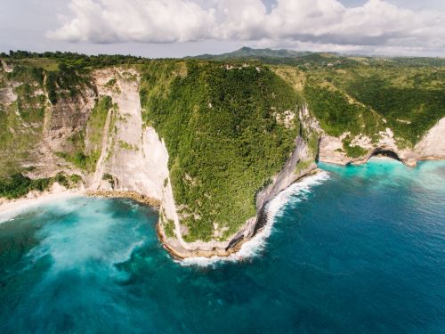 Free Breathtaking aerial view of rugged coastal cliffs and turquoise ocean in a serene natural landscape. Stock Photo
