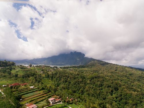 Free Breathtaking aerial view of terraced fields, forests, and mountains under a cloudy sky. Stock Photo