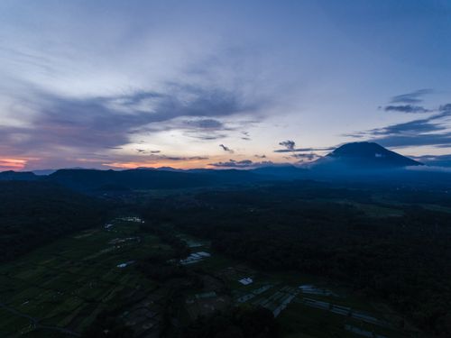 Free A peaceful aerial landscape with mountains, fields, and a vivid twilight sky. Stock Photo