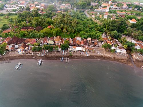 Free Stunning aerial view of a tropical fishing village by the seaside with boats and lush greenery. Stock Photo