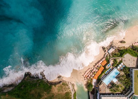 Aerial view of a beautiful beach resort with turquoise waters and sandy shores.