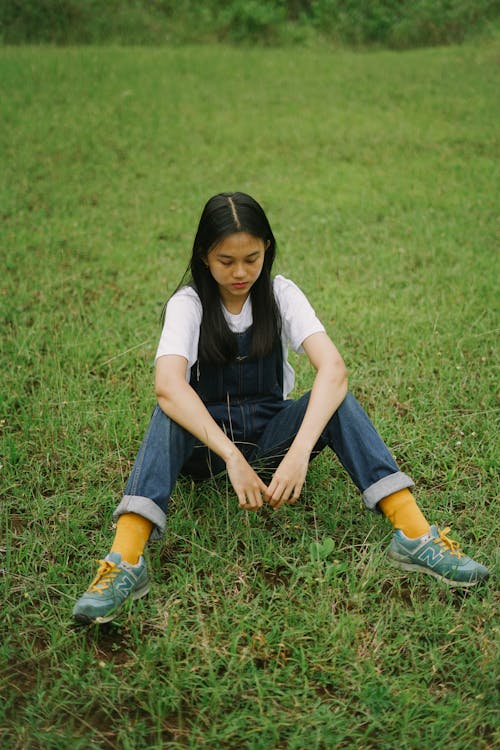 Free A Woman in Overalls Sitting on the Grass  Stock Photo