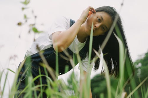 A Woman in White Shirt and Denim Jumper on Green Grass Field