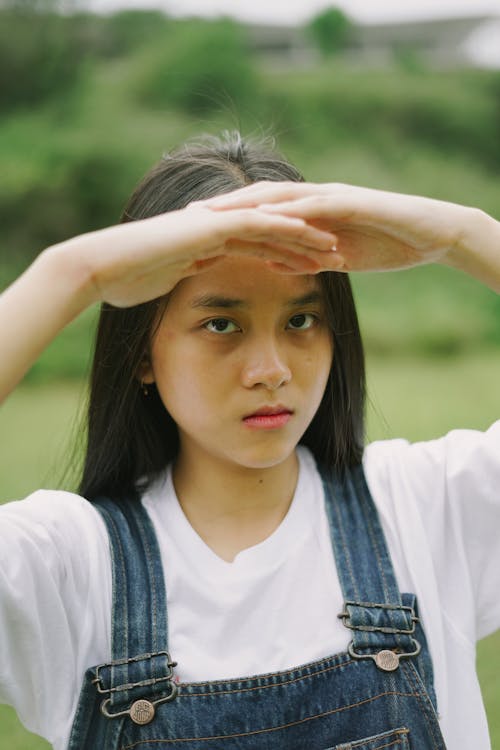 A Woman in White Shirt and Denim Jumper Looking with a Serious Face