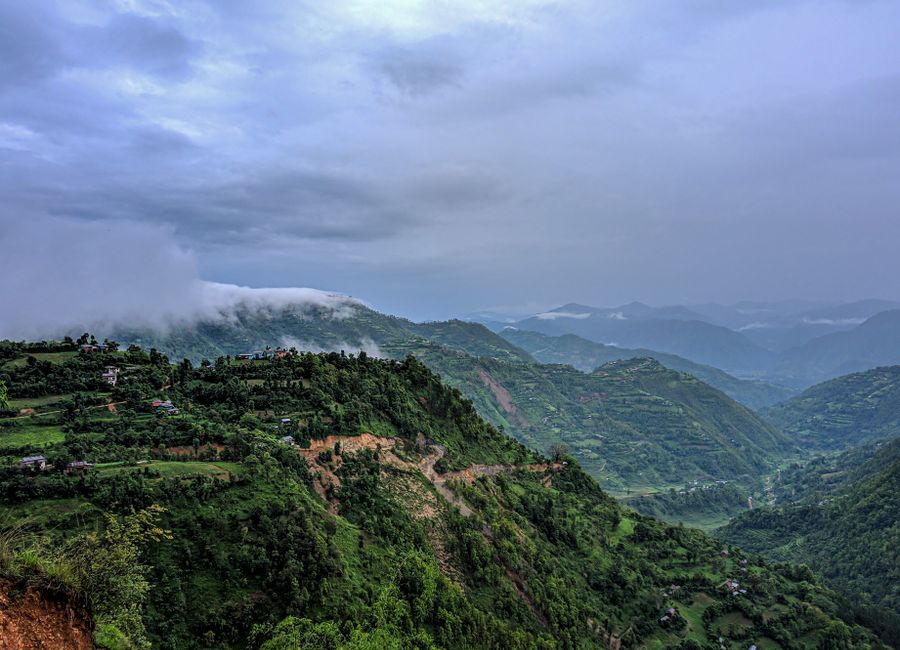 Breathtaking aerial view of lush green hills and valleys under cloudy skies in Nepal.