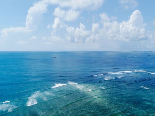 Free Aerial view of ocean waves and blue sky with white clouds, capturing a tranquil seascape. Stock Photo