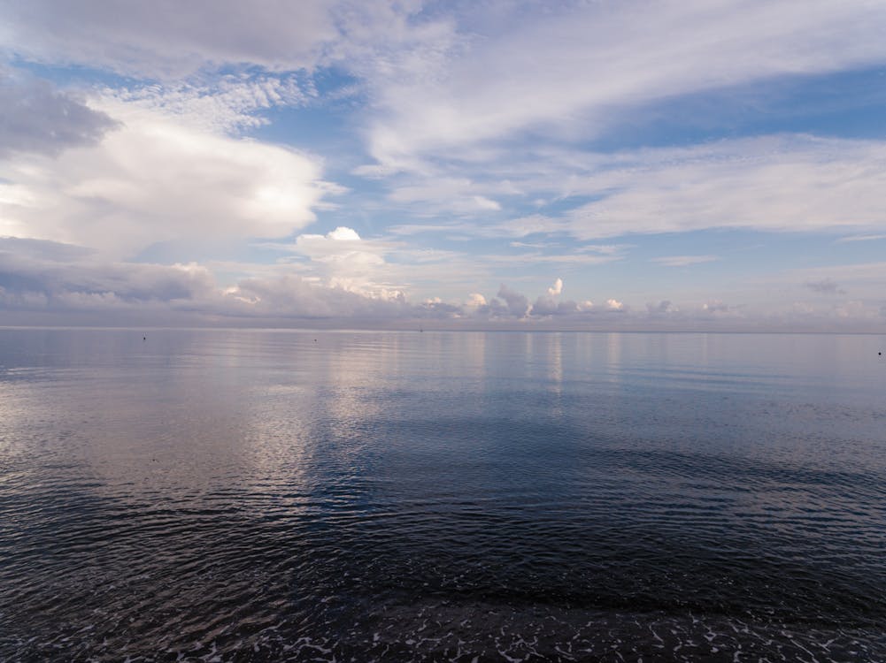 A Calm Sea Under a Blue Sky With White Clouds · Free Stock Photo