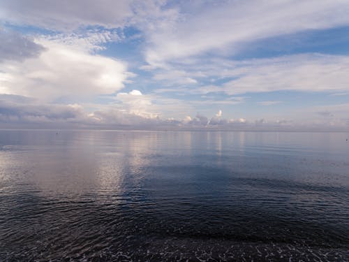 A Calm Sea Under a Blue Sky With White Clouds