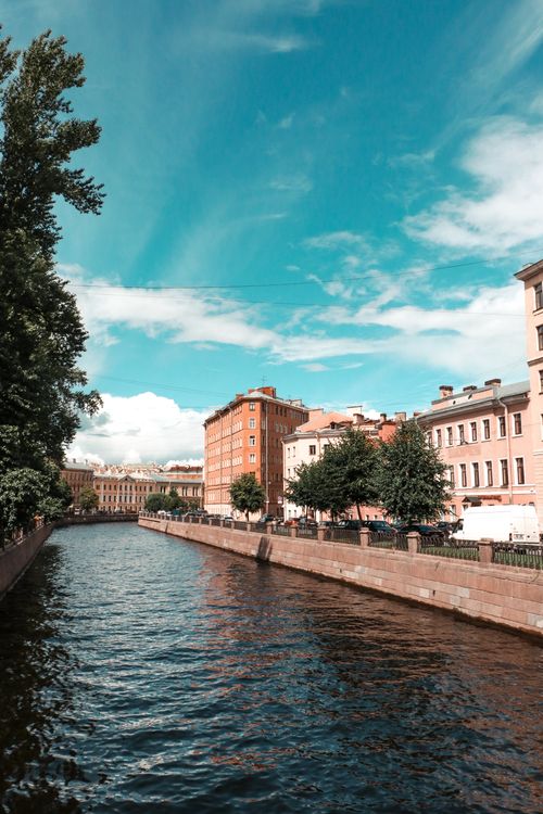 Free A charming urban canal with historic buildings and a vibrant blue sky. Stock Photo