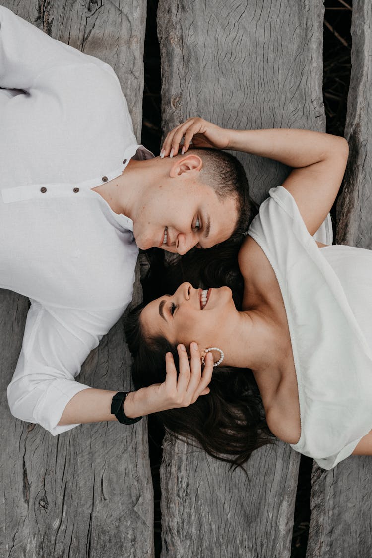 A Couple Lying On A Wooden Deck