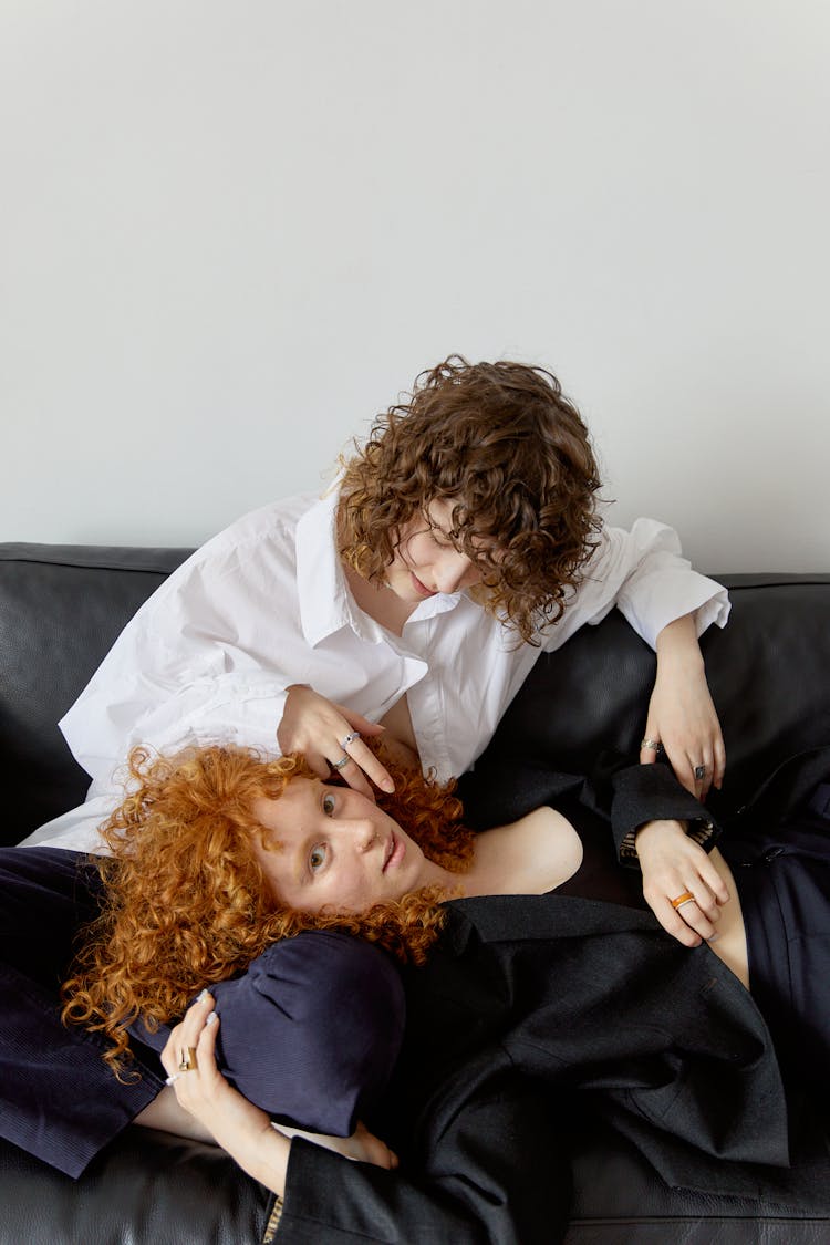 A Couple Sitting And Lying On A Black Couch