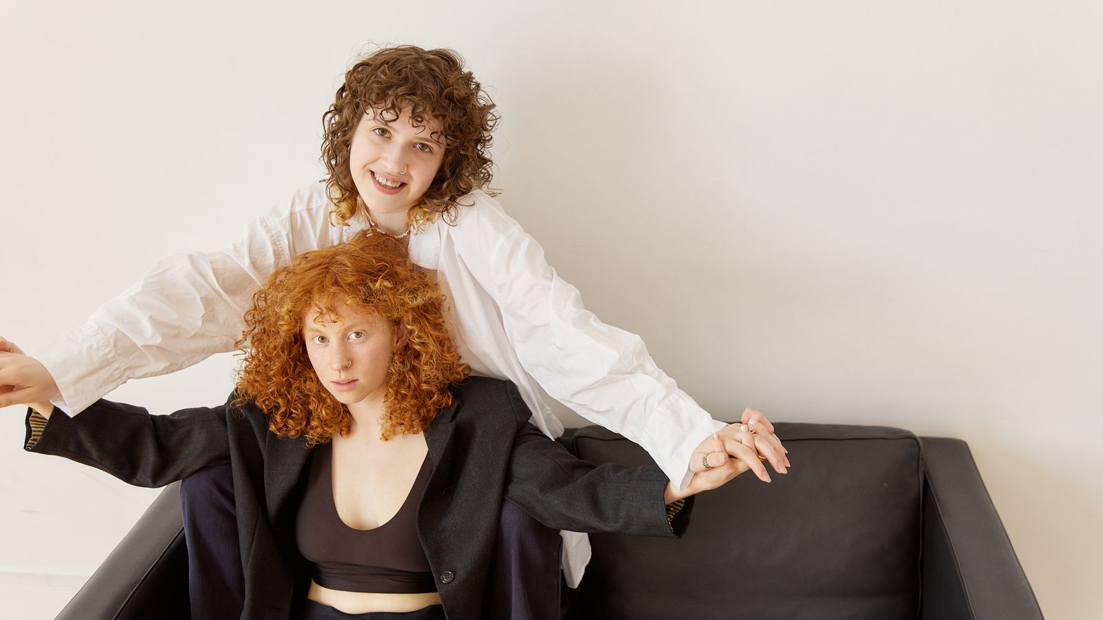 Two adults holding hands on a black sofa