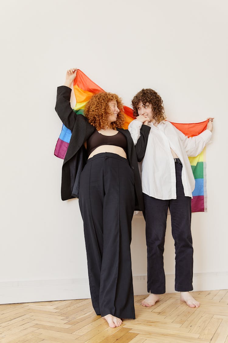 Women Looking At Each Other While Holding Colorful Flag