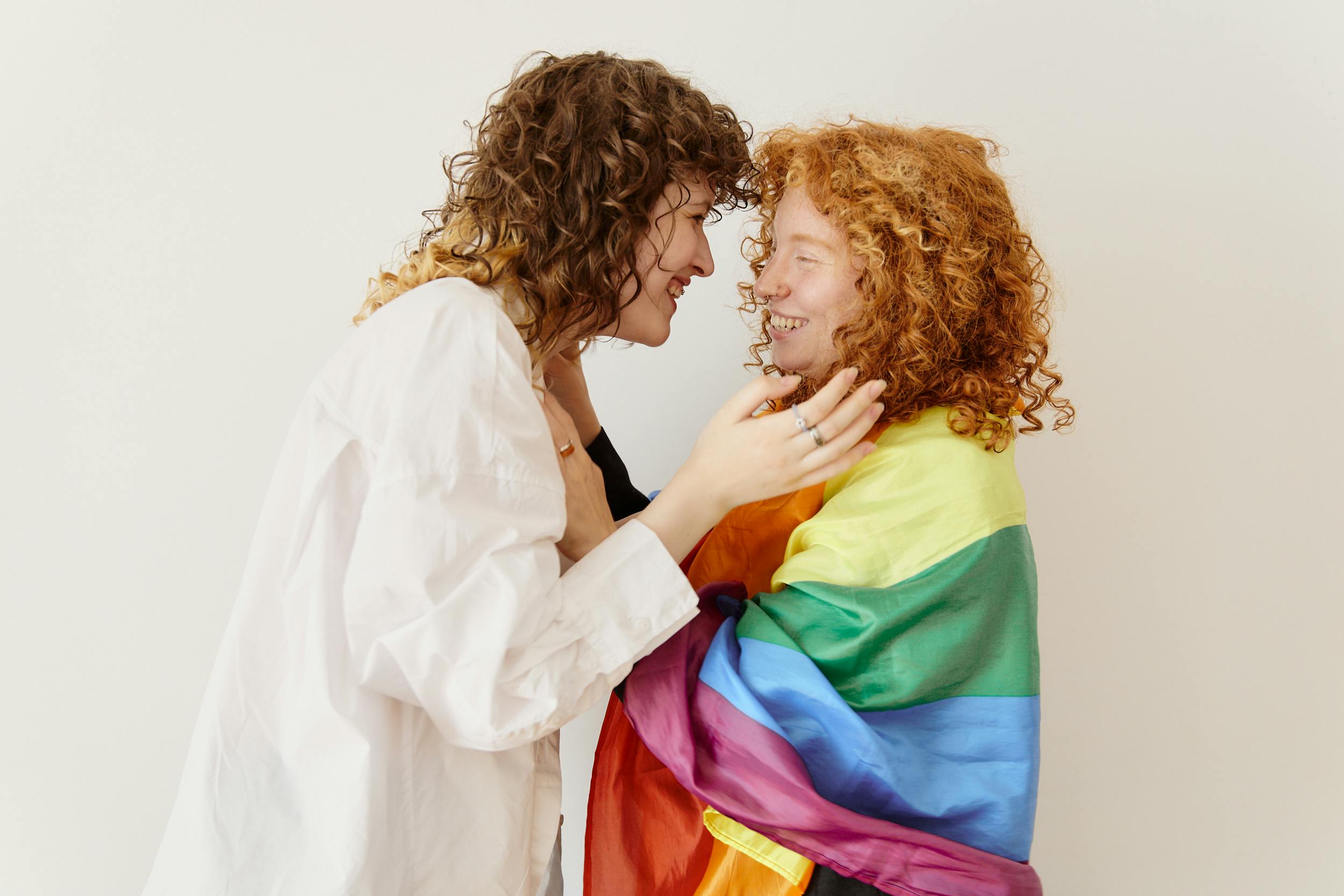 a same sex couple with curly hair laughing at each other