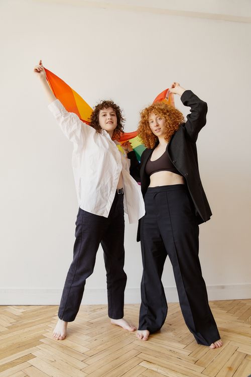 Free Two women joyfully holding a pride flag indoors, embodying diversity and inclusion. Stock Photo