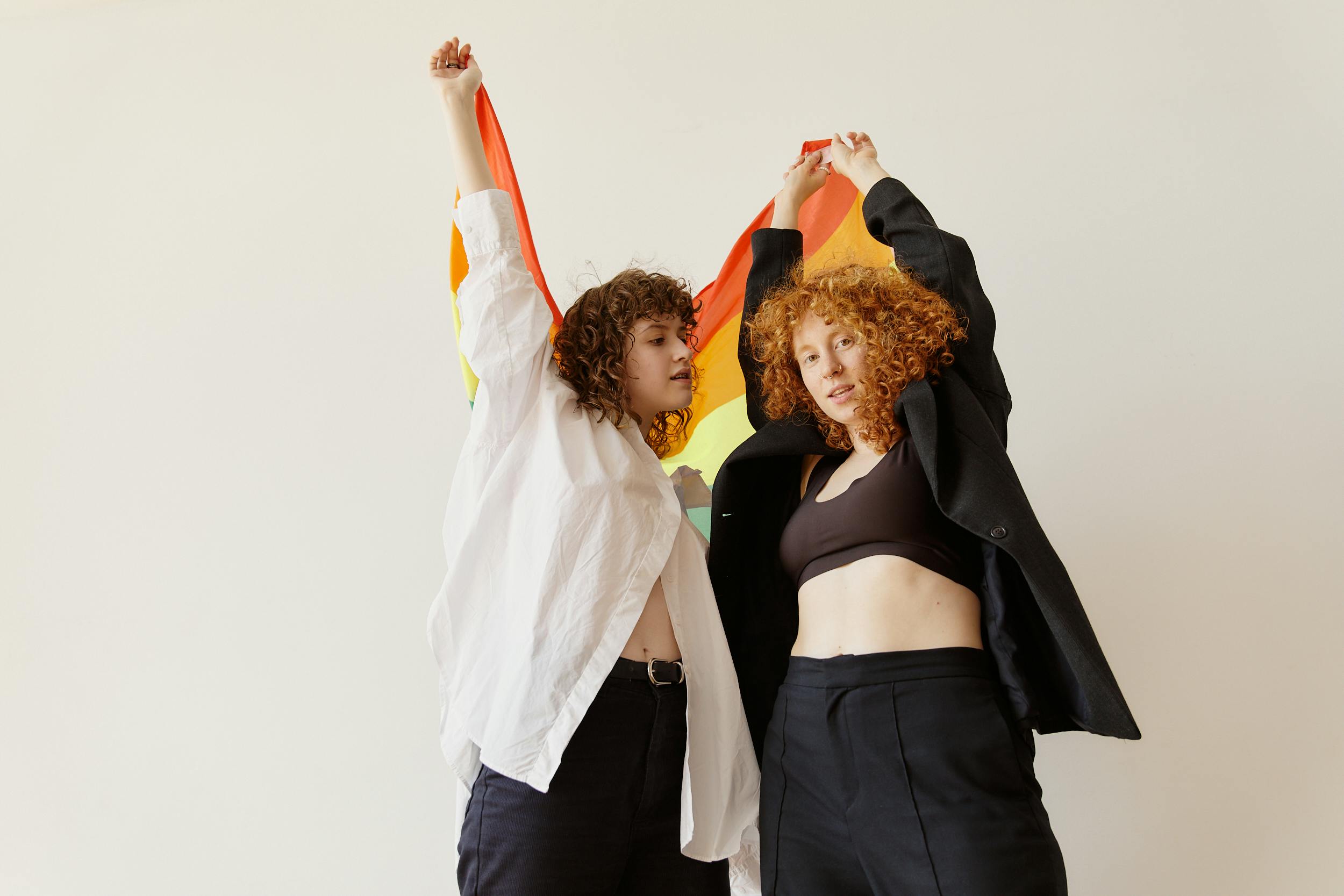 a low angle shot of women standing together while holding a colorful scarf