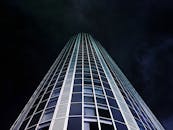 在戏剧性的黑暗天空下，现代摩天大楼的玻璃立面呈现出低视角