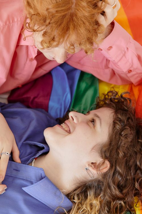 Free Happy couple embracing on a rainbow flag, celebrating love and diversity. Stock Photo