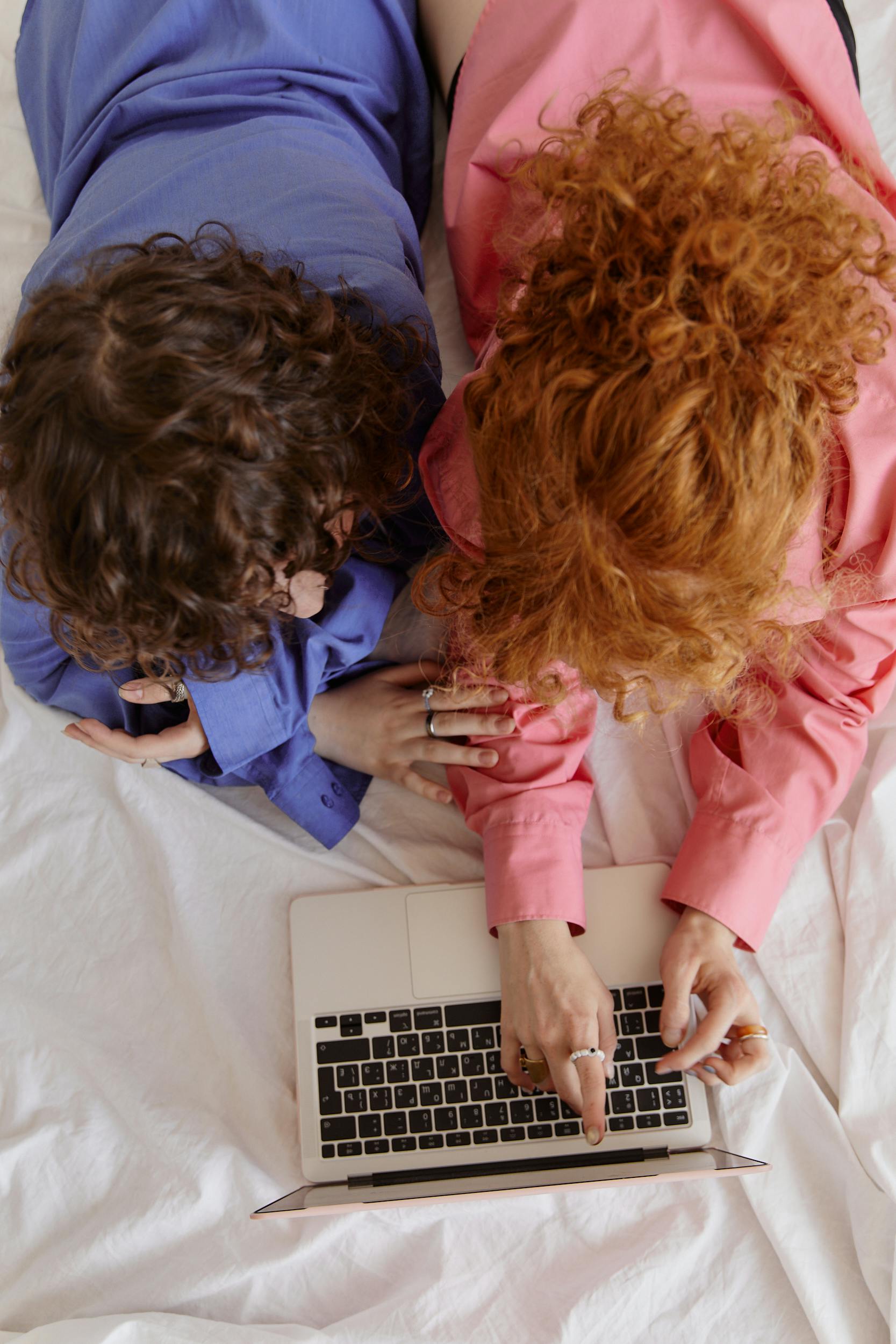 women lying on the bed while using laptop