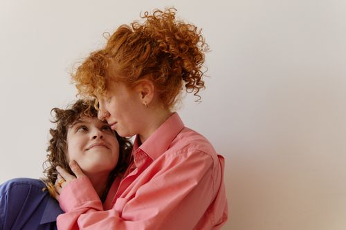 Free Intimate moment of a loving LGBTQ couple with curly hair embracing and smiling. Stock Photo