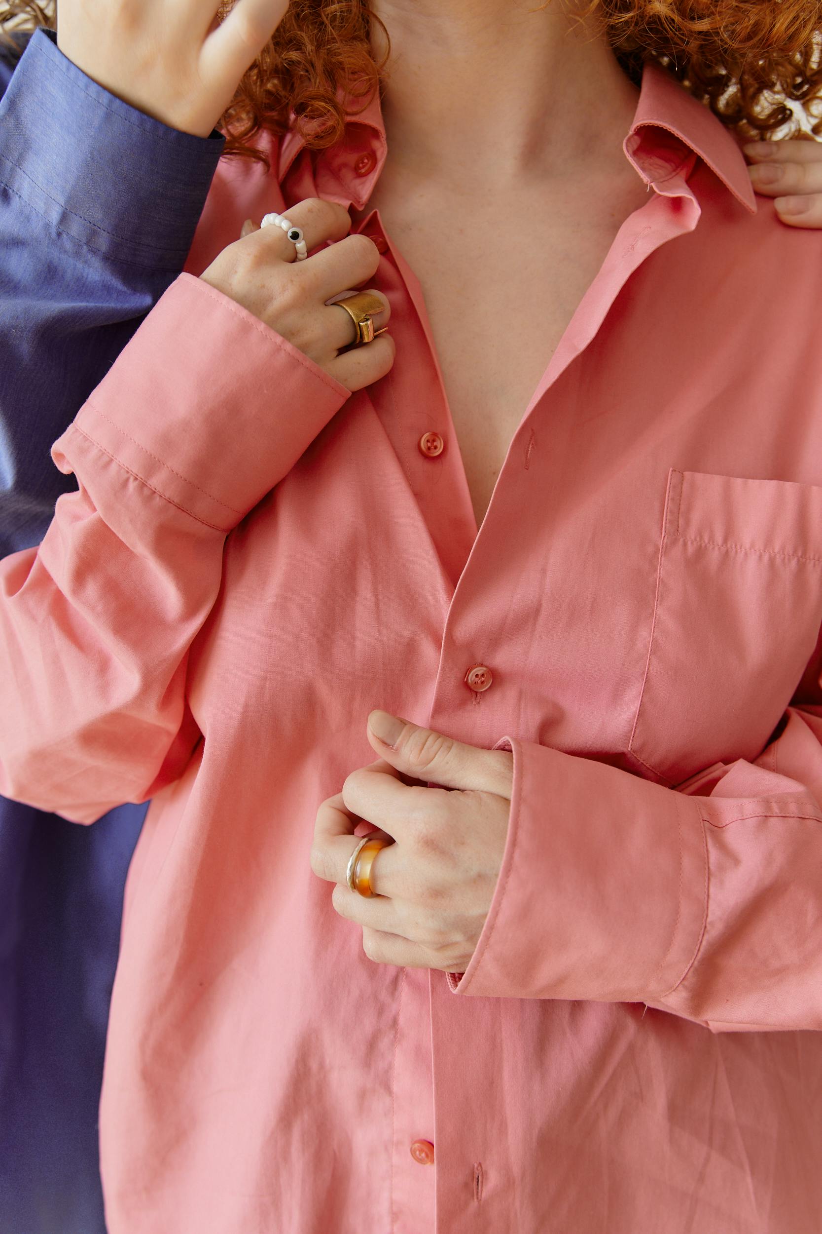 Intimate close-up of two people embracing, wearing a pink blouse and showing jewelry.