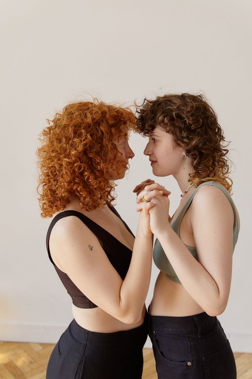 Free Two women share an intimate moment holding hands indoors, capturing a sense of connection. Stock Photo