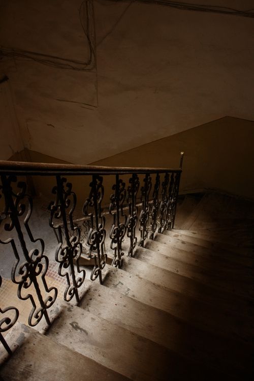 Free A dark, antique staircase with ornate metal railings and dramatic lighting indoors. Stock Photo